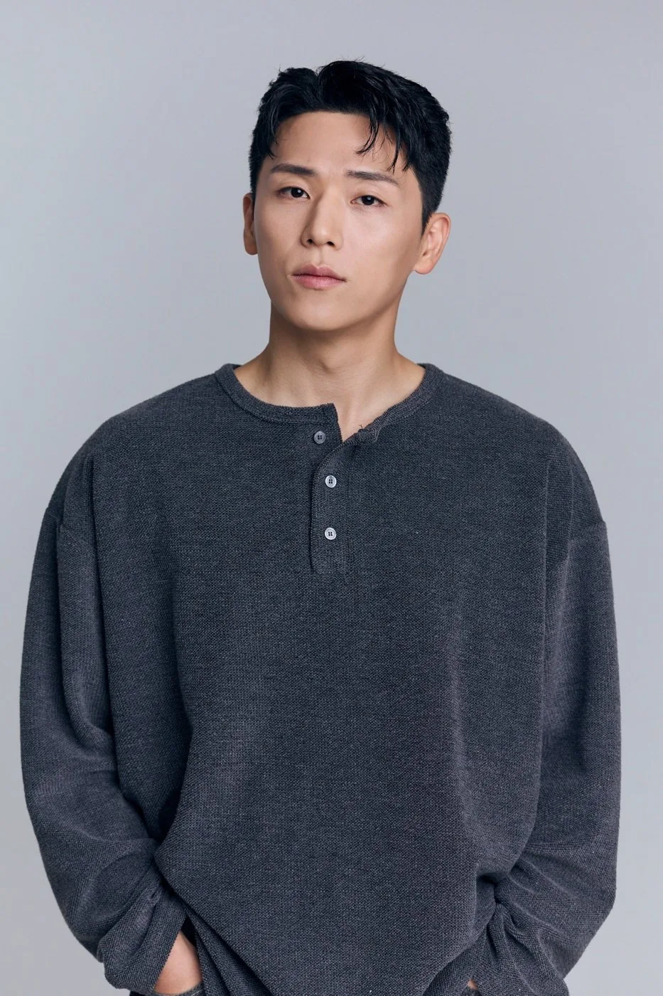 짙은 회색 상의를 입고 카메라 앞에 선 도건우