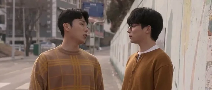 거리에서 갈색 계열 옷을 입은 정수와 수현이 서로를 바라본다.