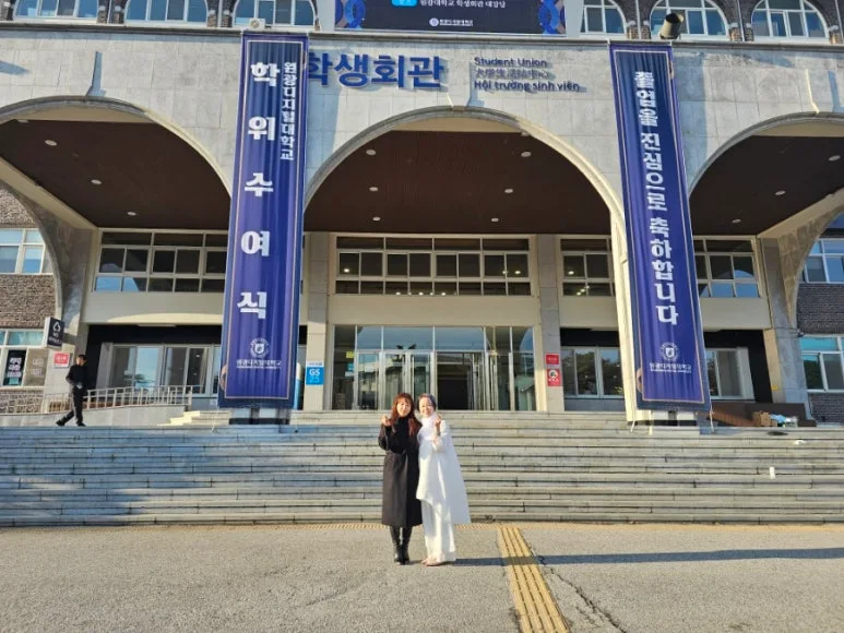 원광디지털대학교 학위수여식 현수막이 걸린 건물 앞에 함께 선 두 대표